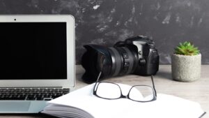 laptop, kamera, blomma, anteckningsblock och glasögon